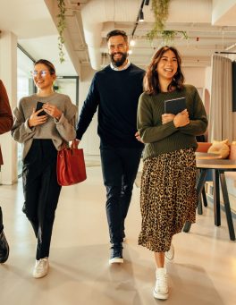 Multiethnic businesspeople walking through a modern office in the morning. Team of happy businesspeople smiling cheerfully. Group of diverse entrepreneurs working together in a co-working space.